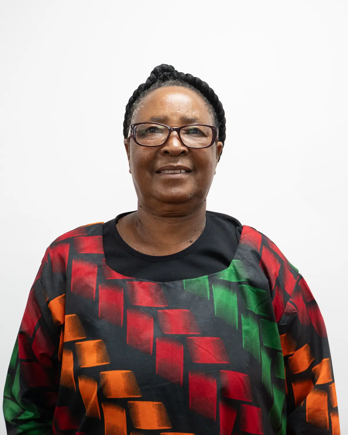 A woman in a red, green and black patterned dress smiling at a Black History Month gathering.