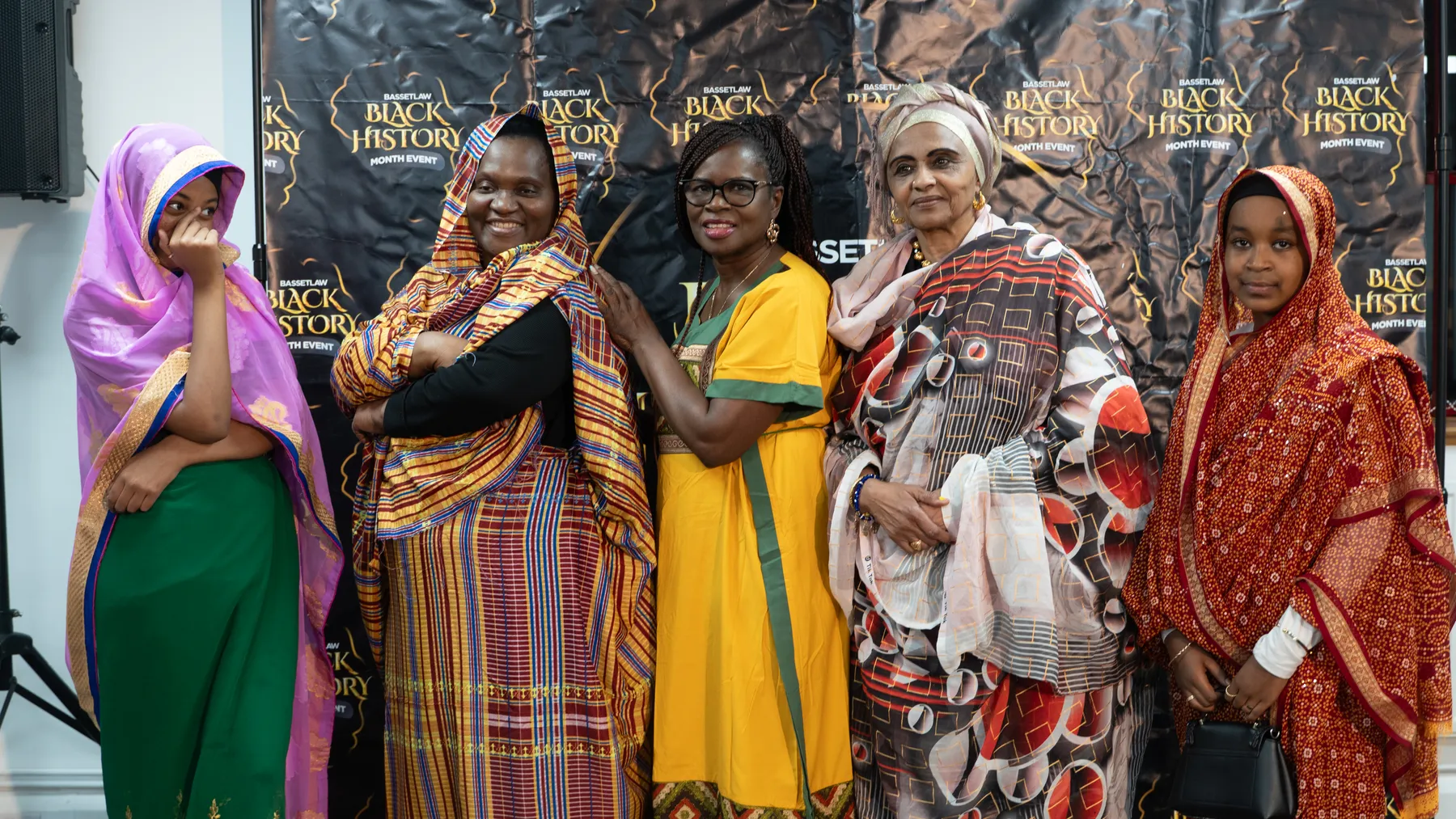 Five women wearing colourful outfits at a Black History Month gathering.