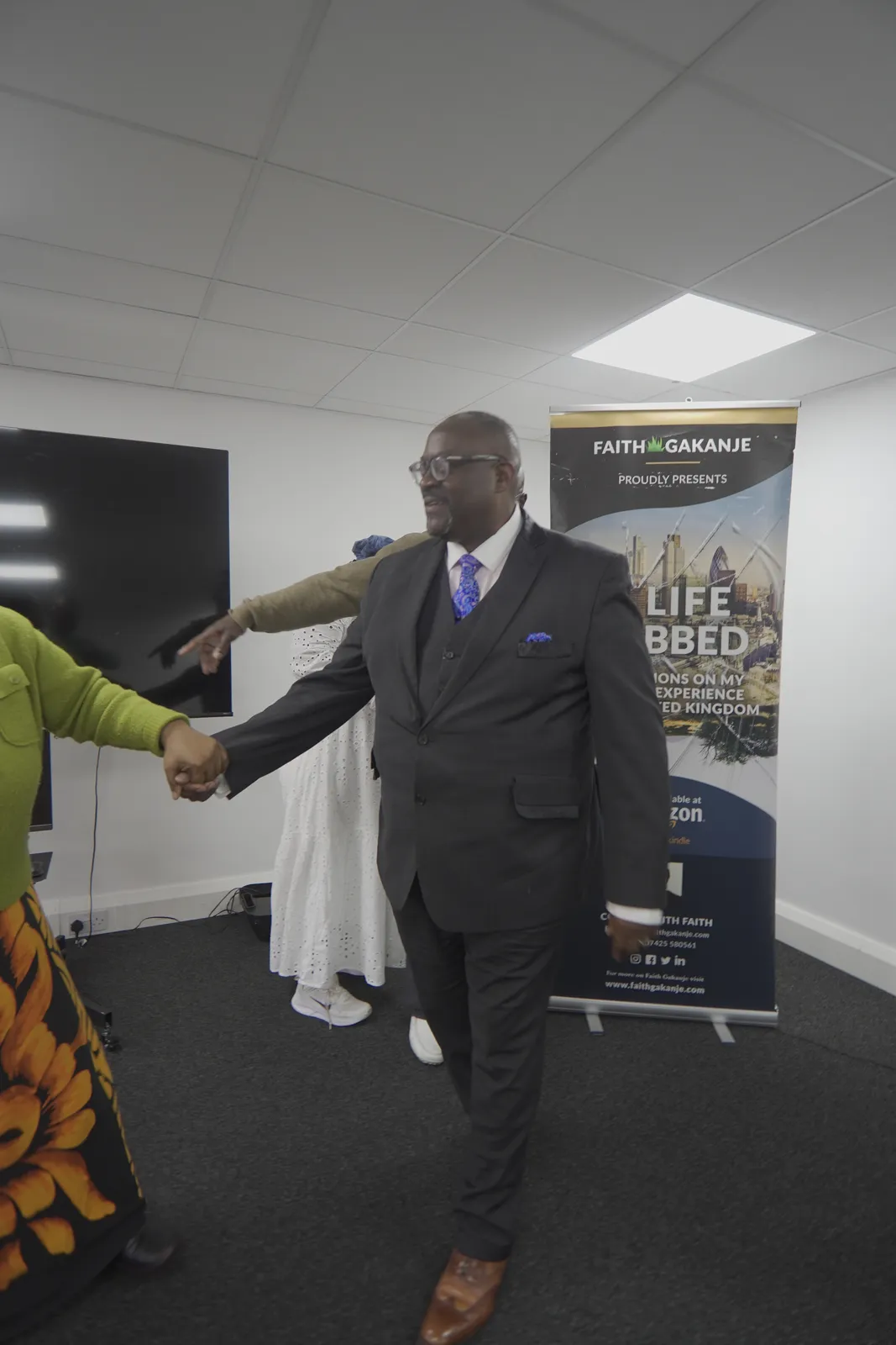 A visitor in a suit greeting Faith at the AWEF office.