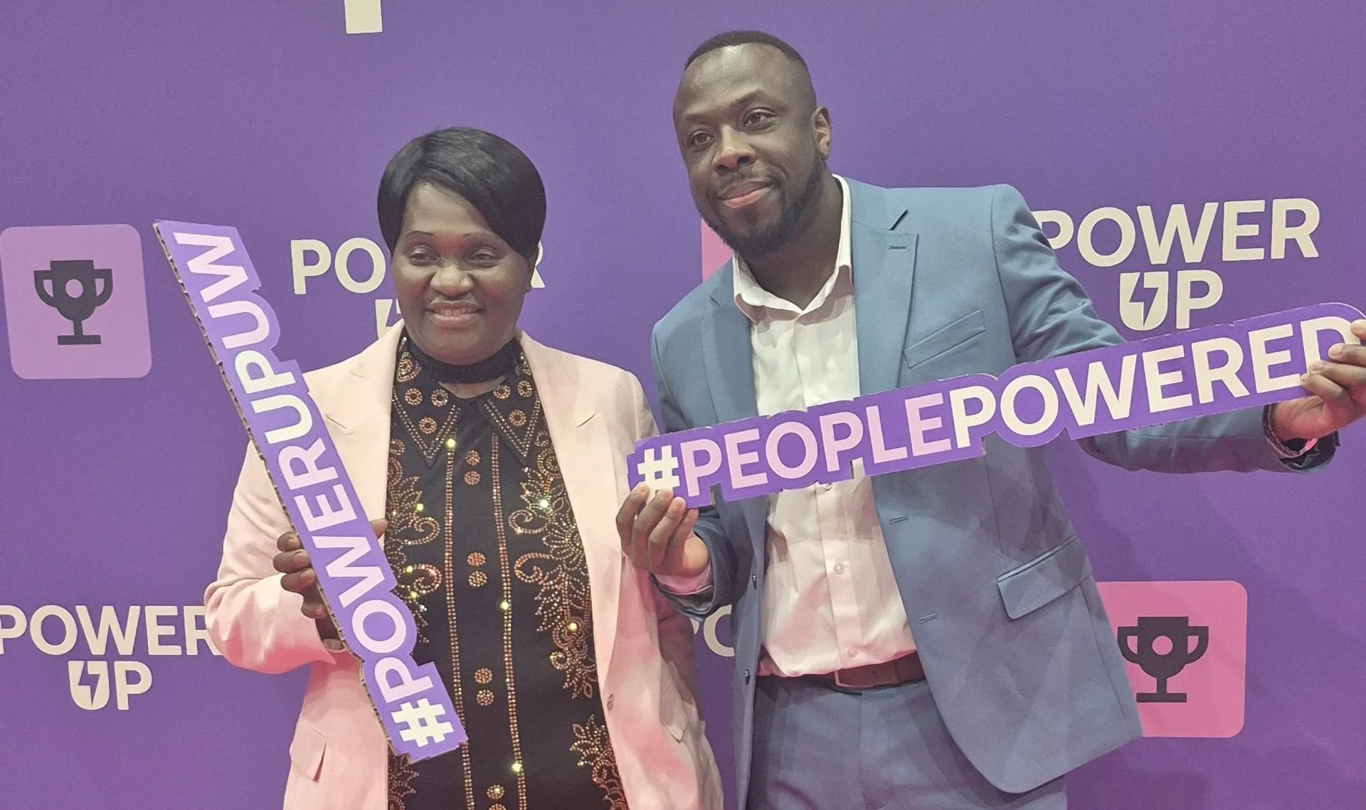 Faith Gakanje-Ajala and another attendee holding People Powered signs at a community power event.