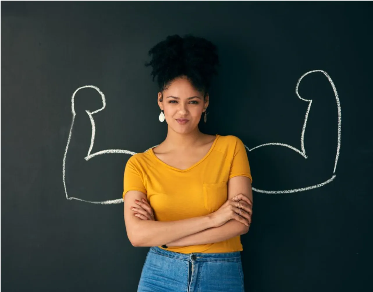 A woman with her arms folded in front of chalk-drawn strong arms.