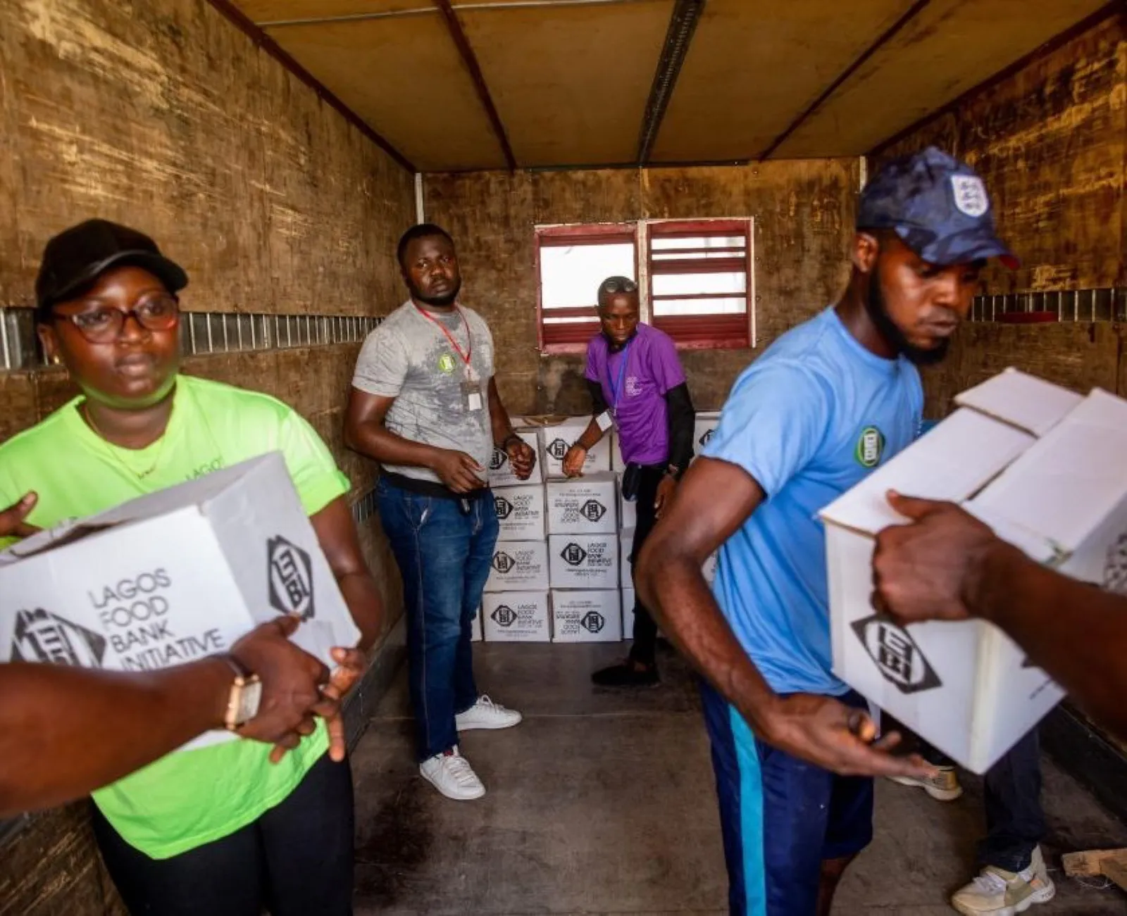 Volunteers carrying boxes of supplies in a warehouse.