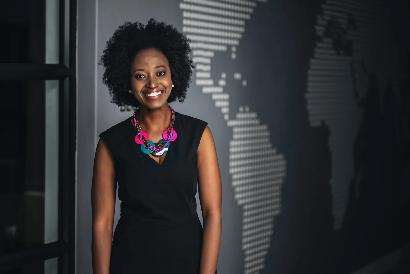A woman smiling in front of a world map.