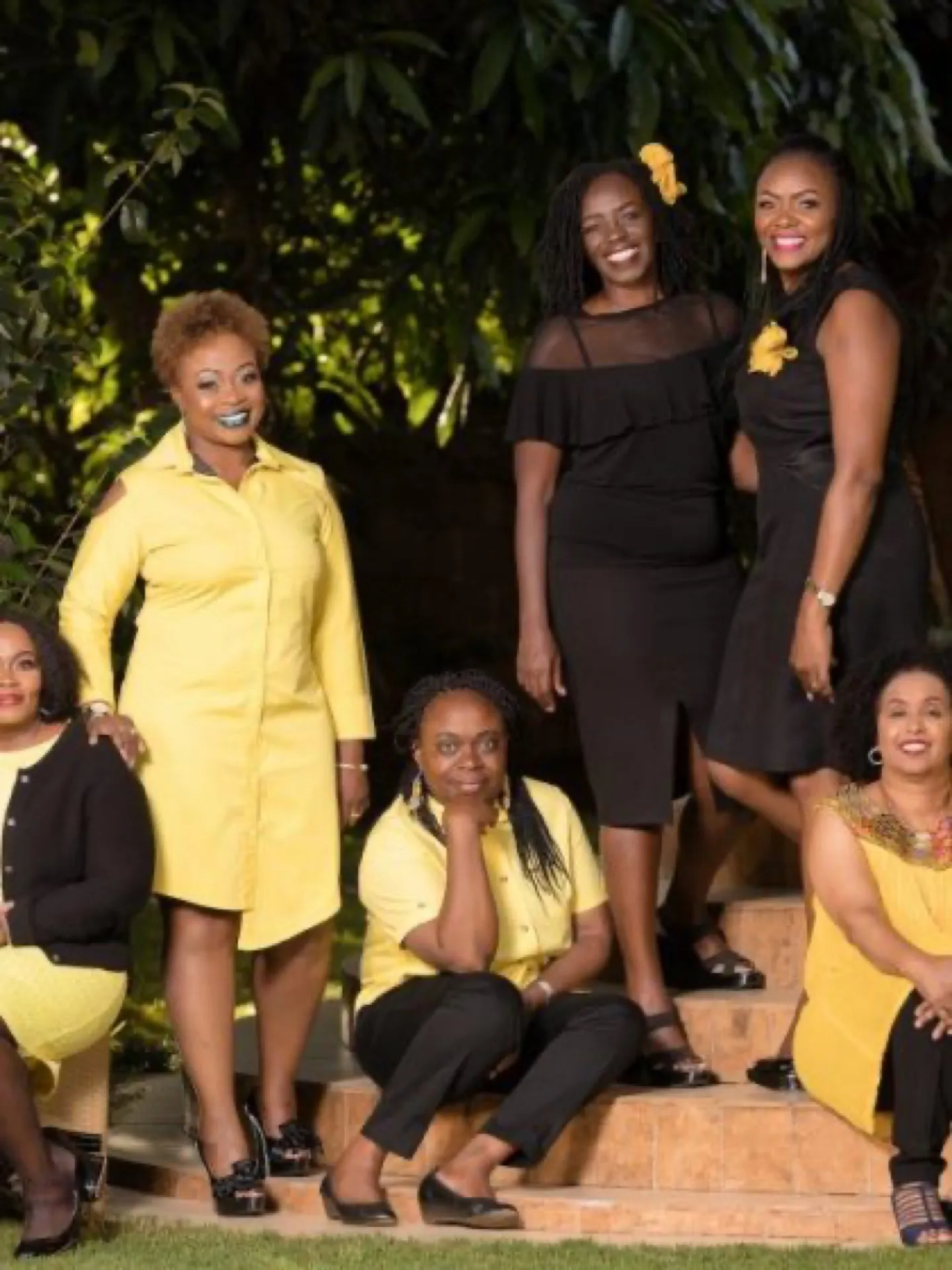 Women in yellow and black outfits gathered outdoors in the evening.